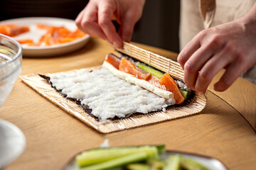 Making sushi at home, female hands rolling sushy
