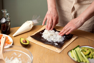 Making sushi at home. Adding rice over nori.