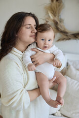Loving mother gently embraces cheerful baby in cozy home interior