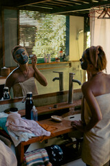Facial skin care. Woman applying cleansing mask, portrait
