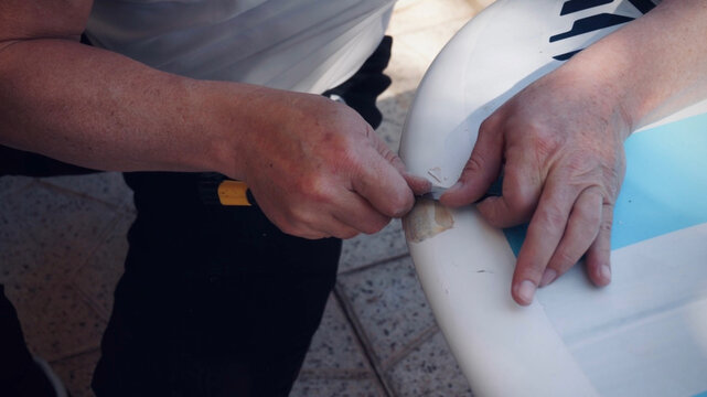 Man repairing windsurf board reparation - Powered by Adobe