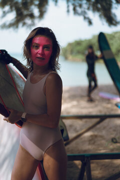 Portrait of mid adult woman with surfboard at beach