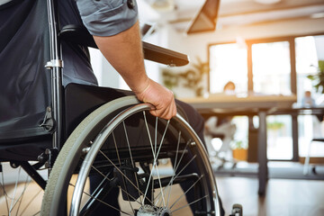 Obraz premium A person using a wheelchair working at a desk in a small, modern office