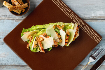 Chicken Caesar salad served on a porcelain plate with crusty bread
