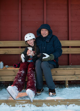 grandfather and granddaughter sat hugging after ice skating outdoors