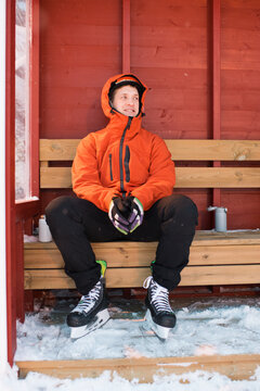 man sitting on the side lines after ice skating outdoors in Sweden
