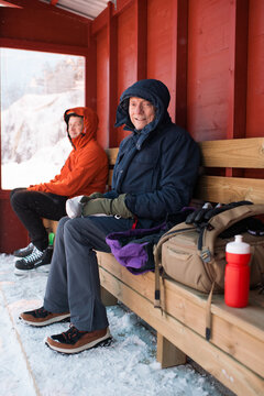 pensioner sitting watching his family ice skate outdoors in sweden
