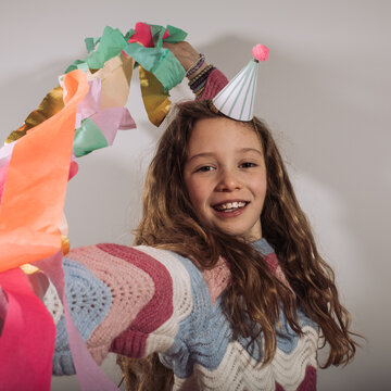 10 year old girl posing at her birthday party with streamers and a hat
