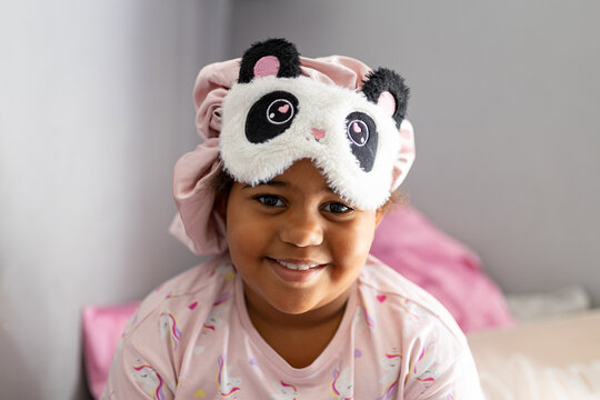 Smiling young girl with eye mask and hair bonnet on