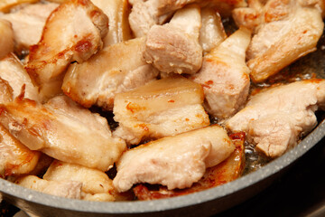A pan of pork chops is cooking on a stove