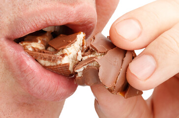A man is eating a chocolate bar with a bite taken out of it