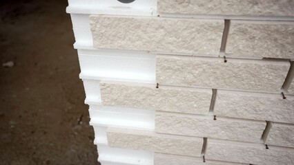Construction workers install an insulating panel with integrated brick facade for energy efficient building