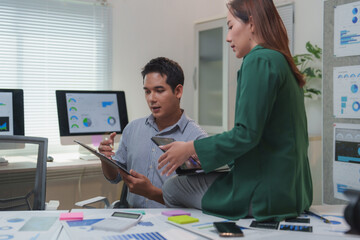 Asian businesspeople discussing business performance using charts and reports on desk