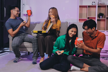 Fototapeta premium Happy young friends group having lunch at home. Asia family party eating pizza food and laughing enjoying meal while sitting at dining table together at house. Celebration holiday and togetherness.