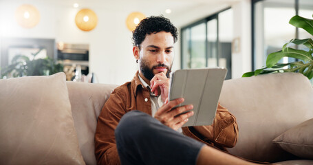 Man, relax and thinking on couch with tablet, social media and ideas for new home improvement....