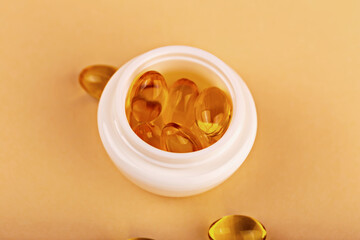Mockup. Jar filled with omega vitamin capsules on pastel background. Capsules symbolize skincare vitamin care concept. Omega capsules in cosmetic jar highlight vitamin-rich beauty treatment