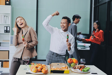 Asian office colleagues and friends enjoy a daytime BBQ with pizza and beer, celebrating Halloween and cheering for their favorite soccer team, creating a lively atmosphere filled with joy.