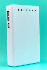 A white power bank device resting on a turquoise surface