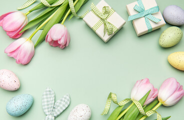Easter eggs, tulips and gift boxes forming a frame on light green background