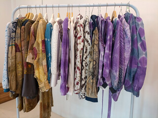 curated display of traditional Indonesian batik garments and fabrics, neatly arranged on a wooden...