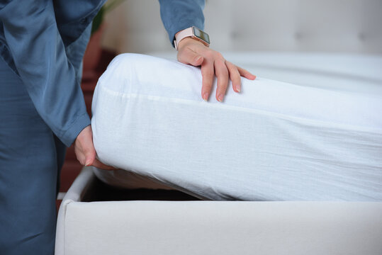 Woman's hand puts a cover on the mattress to protect it from water and house dust mites