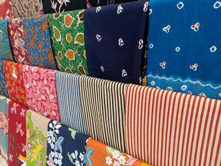 curated display of traditional Indonesian batik garments and fabrics, neatly arranged on a wooden...