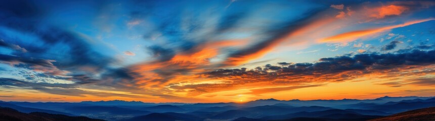 Obraz premium Vivid Sunset Over Mountain Range with Dramatic Sky and Clouds