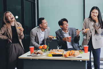 Asian office colleagues and friends enjoy a daytime BBQ with pizza and beer, celebrating Halloween and cheering for their favorite soccer team, creating a lively atmosphere filled with joy.