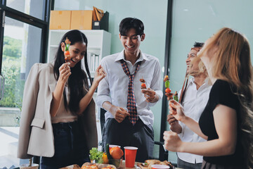 Asian office colleagues and friends enjoy a daytime BBQ with pizza and beer, celebrating Halloween and cheering for their favorite soccer team, creating a lively atmosphere filled with joy.