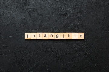 intangible word written on wood block. intangible text on cement table for your desing, concept