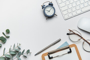 Workspace organizing eucalyptus branches, keyboard, mouse, alarm clock, clipboard, pen, and...