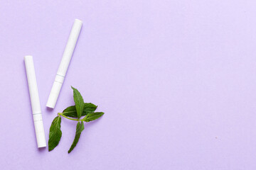 Menthol cigarettes and fresh mint leaves on colored background, Many cigarettes stacked together...
