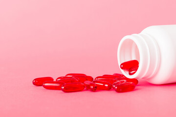 Red pills spilled around a pill bottle. Medicines and prescription pills flat lay background. Red...