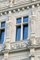 Obraz premium Ornate building facade showcasing intricate sculptural details, decorative elements, and large windows, epitomizing classic architectural beauty.