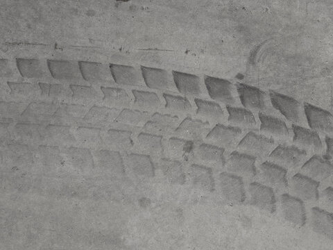 Fototapeta Black and white photography depicting a tire track imprinted on a rough concrete surface