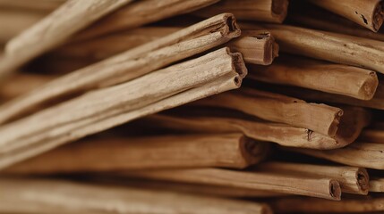 Close-up of a pile of cinnamon sticks. the sticks are light brown in color and appear to be freshly picked. they are arranged in a random, overlapping manner, with some sticks overlapping each other.