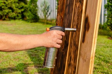 Treating wooden planks with fire from a gas.