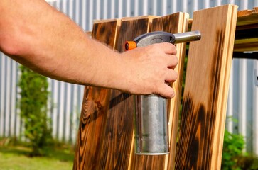 Treating wooden planks with fire from a gas.