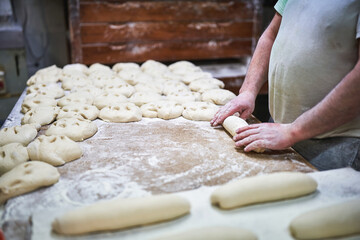 Baker rolling dough into loaves on floured worktable