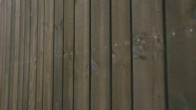 A close-up of a building facade with evenly aligned vertical wooden cladding boards. The screws form a precise line, showcasing skilled installation and craftsmanship