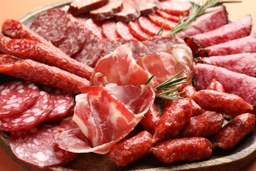 Different smoked sausages slices on orange background, closeup