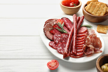 Different smoked sausages slices served on white wooden table, closeup. Space for text