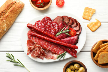 Different smoked sausages slices served on white wooden table, flat lay