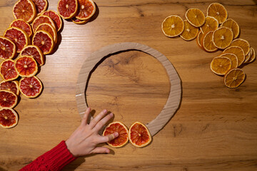 Step 1 DIY process of woman making Christmas arrangement with dried oranges and grapefruits. Series...