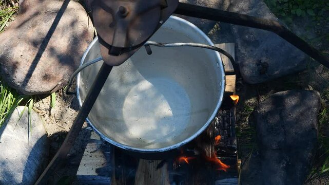 Boiling pot over crackling wood fire showcasing outdoor survival techniques Smoke drifts through fresh air while warm tea and hearty food offer comfort in the untamed beauty of nature Cooking concept