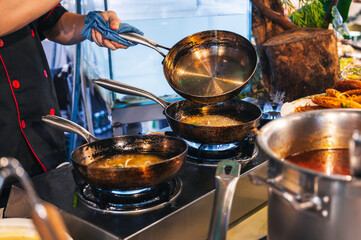 male chef cook prepares food in the kitchen of a restaurant. Cook's hands with a frying pan at stove
