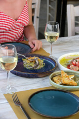 Young woman having dinner in the Mediterranean restaurant. Various dishes served on the table.	
