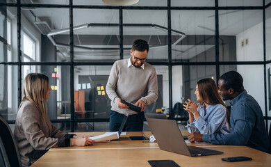By the table. Professional workers are in the modern office together