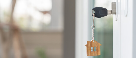 Landlord key for unlocking house is plugged into the door. Second hand house for rent and sale. keychain is blowing in the wind. mortgage for new home, buy, sell, renovate, investment, owner, estate
