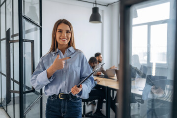 Woman is standing. Professional workers are in the modern office together